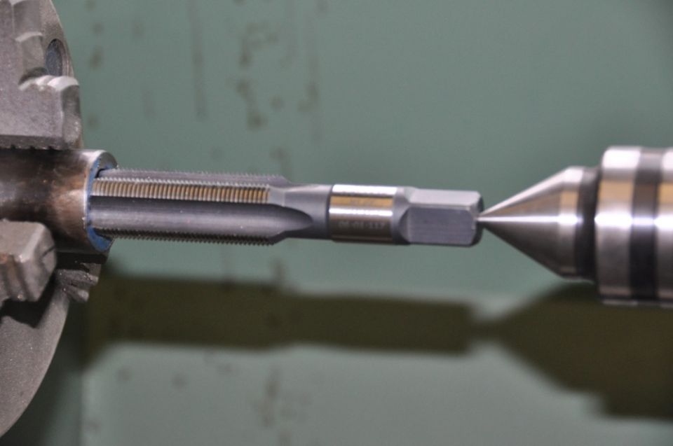 Tap held in chuck, with a center point on the right