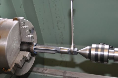 1996 Ford Bronco - A tap is being centered in a lathe chuck, with a wrench holding the tap and a tailstock center supporting it.