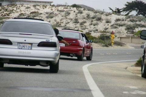 1990 Ford Taurus - A silver 1990 Ford Taurus is seen from the rear, driving on a coastal road.