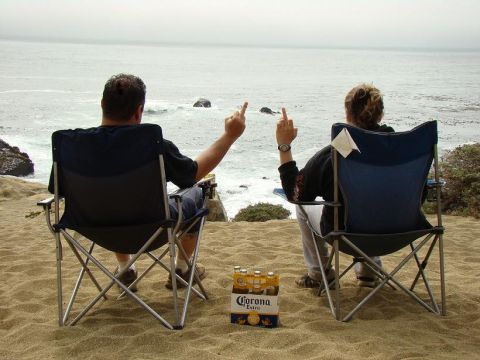 1989 Ford Bronco - Beach scene with two people and a six-pack of Corona Extra, both giving the middle finger to the ocean.
