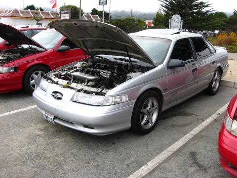 2003 Ford Taurus - Silver sedan with hood open, parked in a lot next to a red vehicle.
