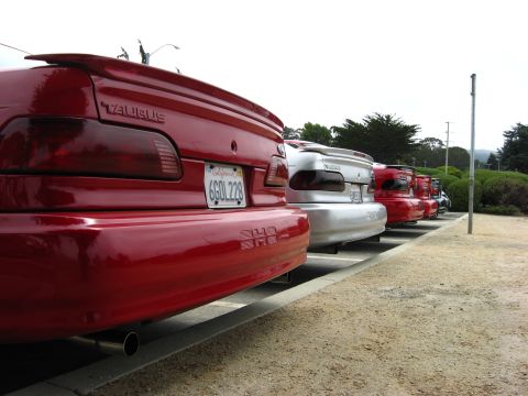 2003 Ford Taurus - Several cars, including a red Ford Taurus, are parked in a lot.
