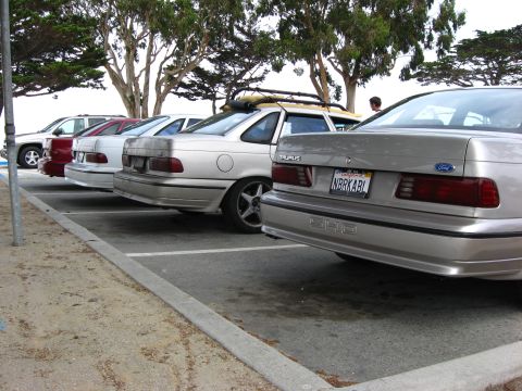 2003 Ford Taurus - Several cars are parked in a lot, including a silver Ford Taurus.