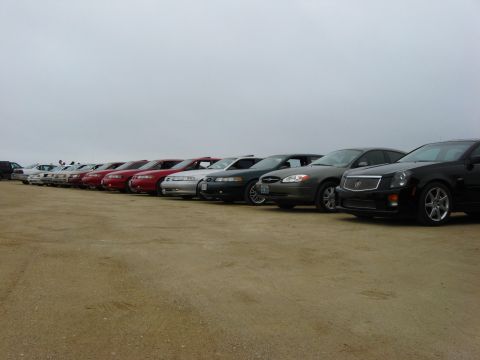 2003 Ford Taurus - Multiple sedans are parked in a line on a dirt lot, with a black Cadillac CTS prominently displayed.