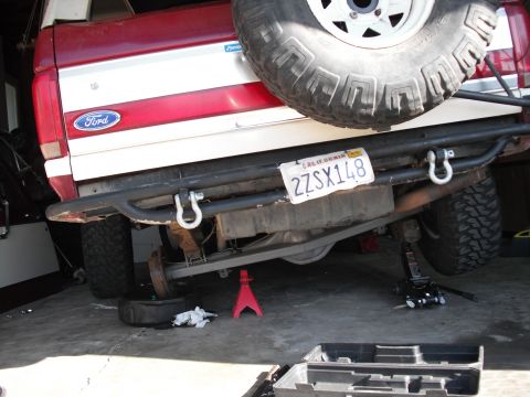 1991 Ford Bronco - The rear axle of a red and white Ford Bronco is visible, supported by a jack and jack stand.