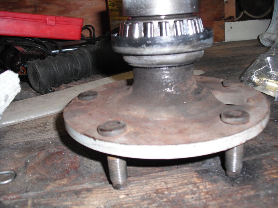 Five-lug wheel hub with tapered roller bearing installed, standing on a wood bench
