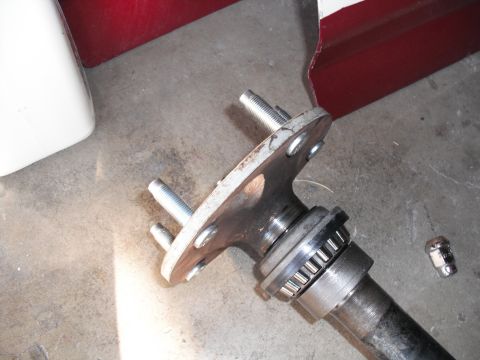 1991 Ford Bronco - Close-up of an axle hub assembly, showing the bearing and studs, with a lug nut nearby.