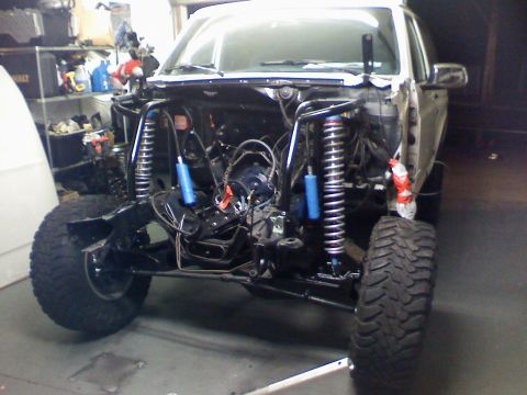 1984 Ford Bronco - This vehicle is in a garage, stripped down for modifications with its engine compartment open.