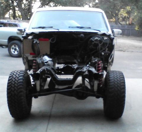 1984 Ford Bronco - Front view of a disassembled truck chassis with exposed suspension and engine components.
