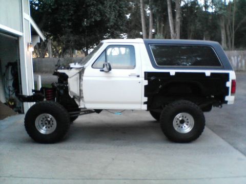 1984 Ford Bronco - This white Ford Bronco, likely from the late 1980s, is shown in a side profile with its front end removed for apparent modifications.