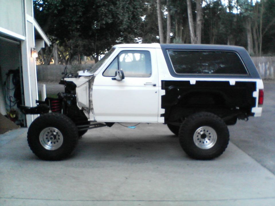 Side view of white Ford Bronco missing front end, with black top