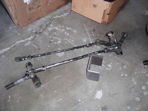 1991 Ford Bronco - A steering linkage assembly is shown lying on a concrete floor, with cardboard boxes in the background.