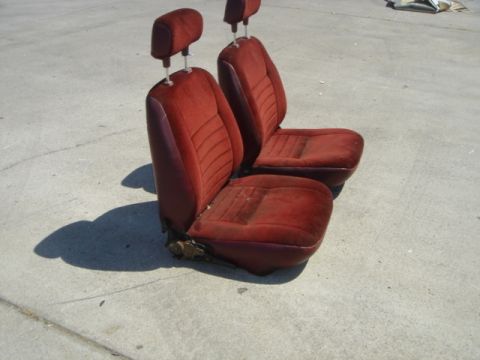 1991 Ford Bronco - Pair of red velour bucket seats with adjustable headrests, likely from an older SUV or truck.