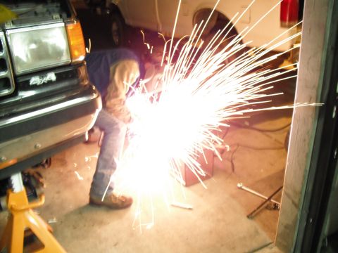 1991 Ford Bronco - A person welds on the front end of a 1991 Ford Bronco, creating a shower of sparks.