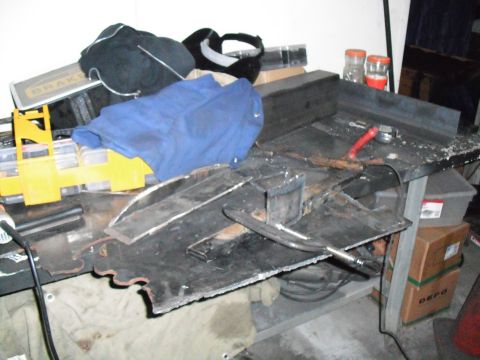 1991 Ford Bronco - A messy workbench is covered in metal pieces, tools, and various items.