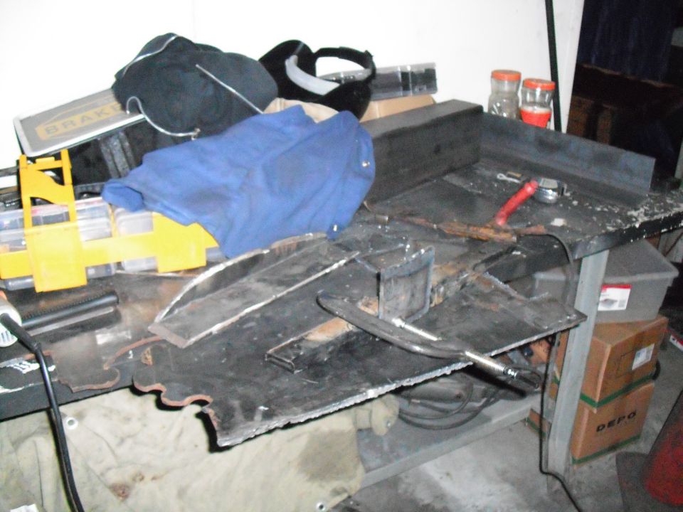 Workbench cluttered with metal scraps, tools, and a blue cloth