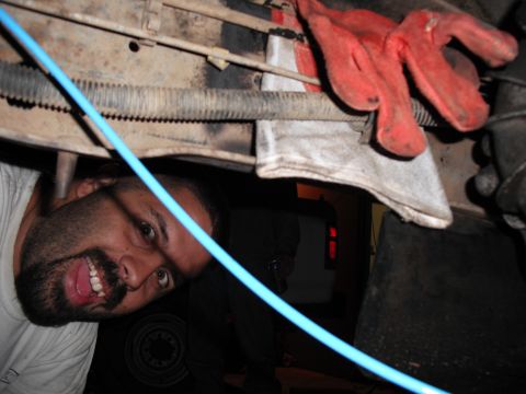 1991 Ford Bronco - Man working on the underside of a vehicle, with tools and parts around him.