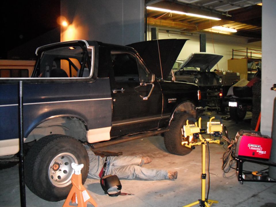 1991 Ford Bronco side view with hood open, mechanic working underneath