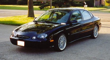 1999 Ford Taurus - A black 1999 Ford Taurus sedan is shown from the front 3/4 angle, parked on a paved surface.
