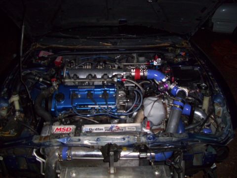 1995 Ford Probe - The engine bay of a car is shown with custom turbo modifications and blue engine components.