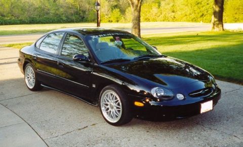 1999 Ford Taurus - This black 1999 Ford Taurus sedan is shown from a three-quarter front view, aftermarket wheels and a clean exterior.