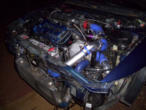 1995 Ford Probe - Custom turbocharged engine bay with extensive modifications, including a large intercooler and vibrant blue piping.