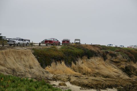 1990 Ford Taurus - A silver 1990 Ford Taurus is parked on a cliffside overlooking a beach, with other vehicles also visible.