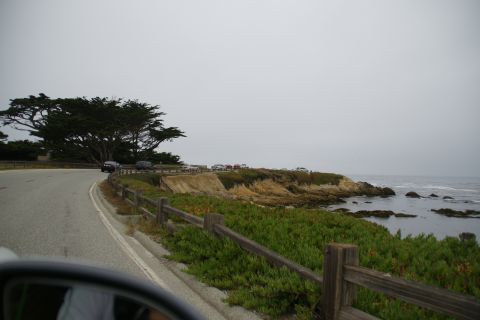 1990 Ford Taurus - View of a scenic coastal highway with parked vehicles on a cloudy day.