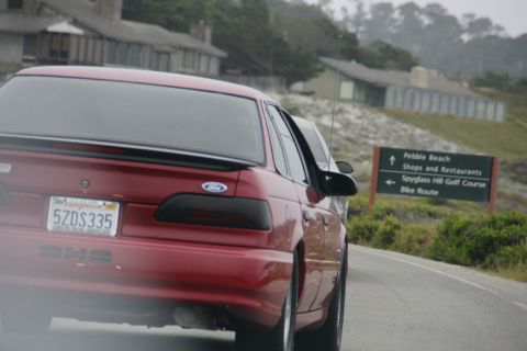 1990 Ford Taurus - A red 1990 Ford Taurus is seen from the rear on a road near Pebble Beach, California.