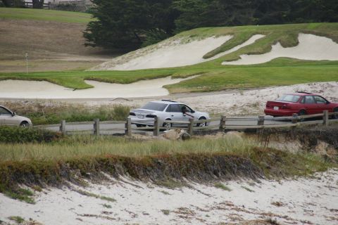 1990 Ford Taurus - A white sedan is seen driving on a road adjacent to a golf course, with a red sedan also visible in the frame.
