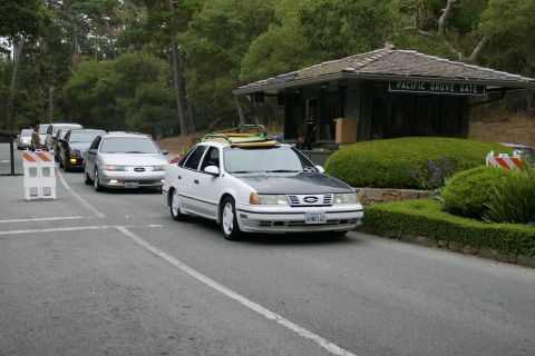 1990 Ford Taurus - Cars queue at Pacific Grove Gate, with a 1990 Ford Taurus carrying surfboards in the foreground.