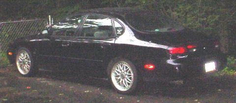 1999 Ford Taurus - Black 1999 Ford Taurus sedan with aftermarket wheels seen from the side.