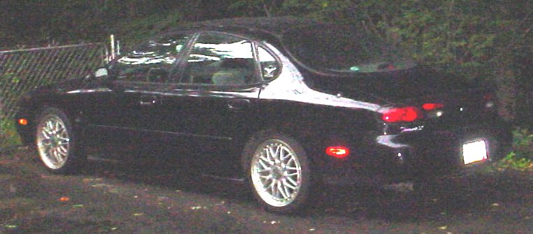 Black Ford Taurus sedan rear three-quarter view at dusk with silver alloy wheels