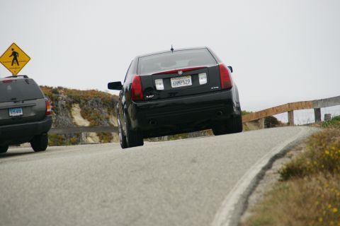 1990 Ford Taurus - Black Cadillac CTS and a dark SUV on a winding road near the coast.