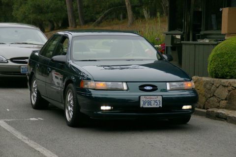 1990 Ford Taurus - Front view of a dark green Ford Taurus, with another Taurus visible behind it.