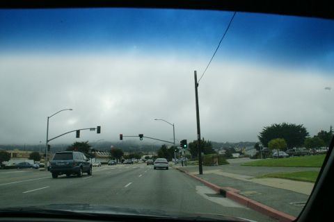 1990 Ford Taurus - A dark blue SUV is seen from behind driving on a road with traffic lights and fog.