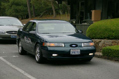 1990 Ford Taurus - This 1990 Ford Taurus sedan is seen from the front 3/4 angle, with another Taurus visible behind it.
