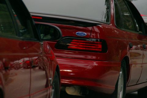 1990 Ford Taurus - Rear view of a red 1990 Ford Taurus, showing its distinctive horizontal taillights and Ford badging.