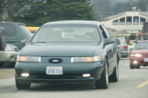1990 Ford Taurus - A 1990 Ford Taurus is seen from the front in traffic, with other vehicles around it.