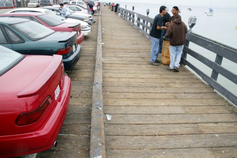 1990 Ford Taurus - A red 1990 Ford Taurus is parked on a pier alongside other vehicles.