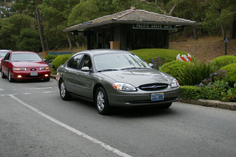 Gray Ford Taurus driving past a gate, red Ford Taurus behind it