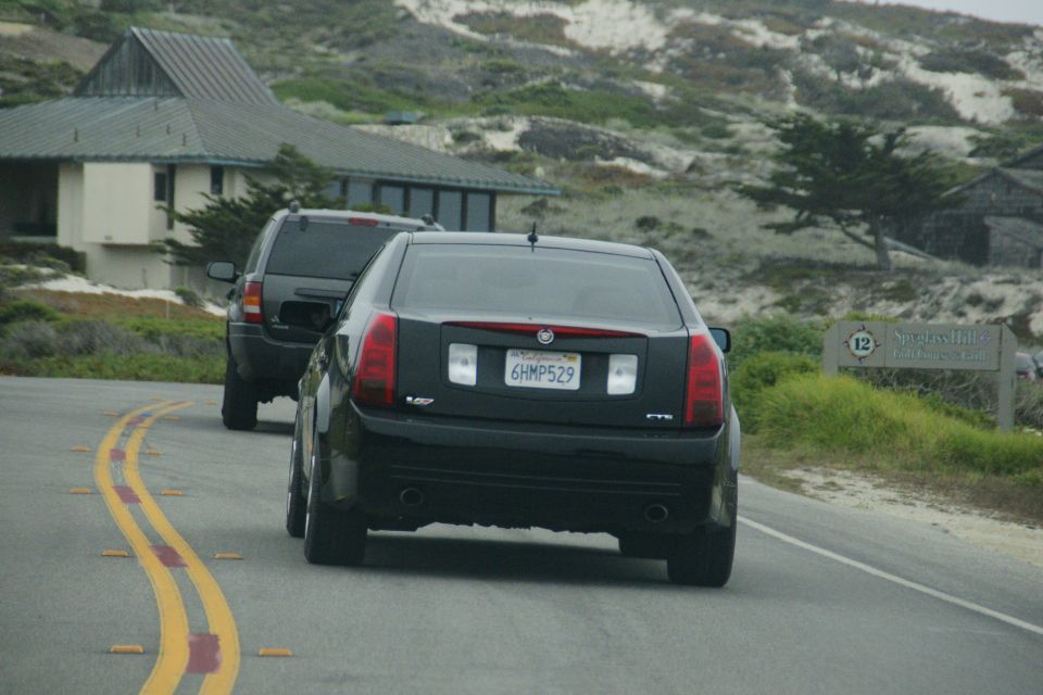 Black sedan with license plate 6HMP529 driving on a road with yellow lines