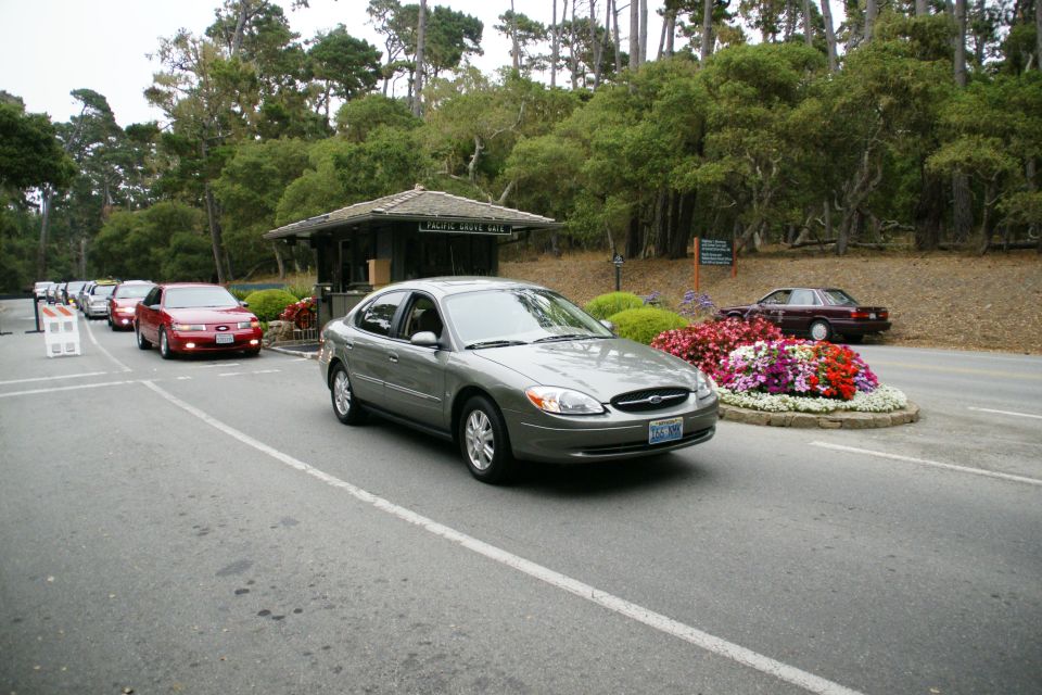Gray Ford Taurus driving past a toll booth with other cars in line