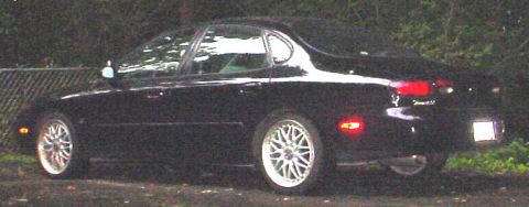 1999 Ford Taurus - A black sedan is parked outdoors with trees in the background and a chain-link fence to its left.