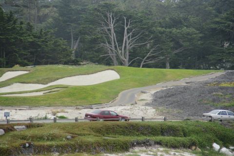 1990 Ford Taurus - A red 1990 Ford Taurus sedan is seen driving on a road with a golf course in the background.