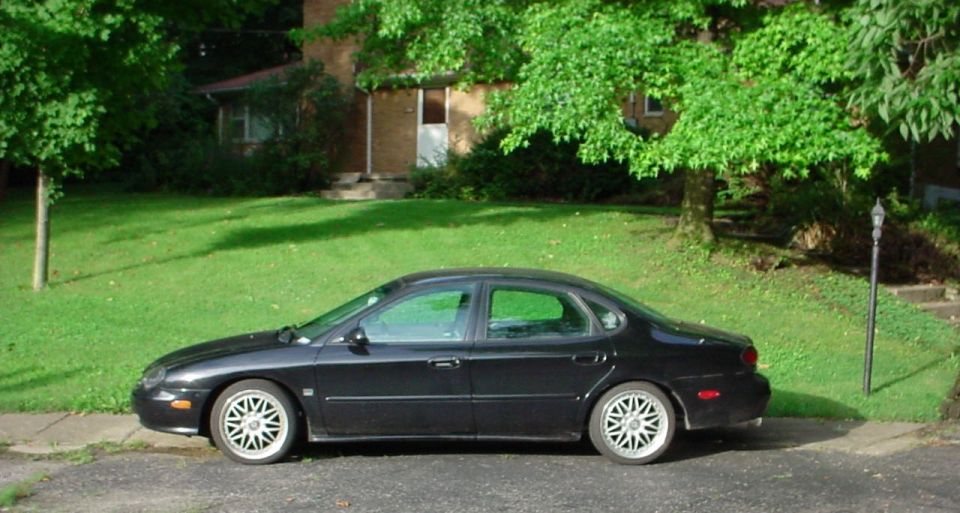 Driver-side profile of lowered black Ford Taurus sedan on silver alloy wheels