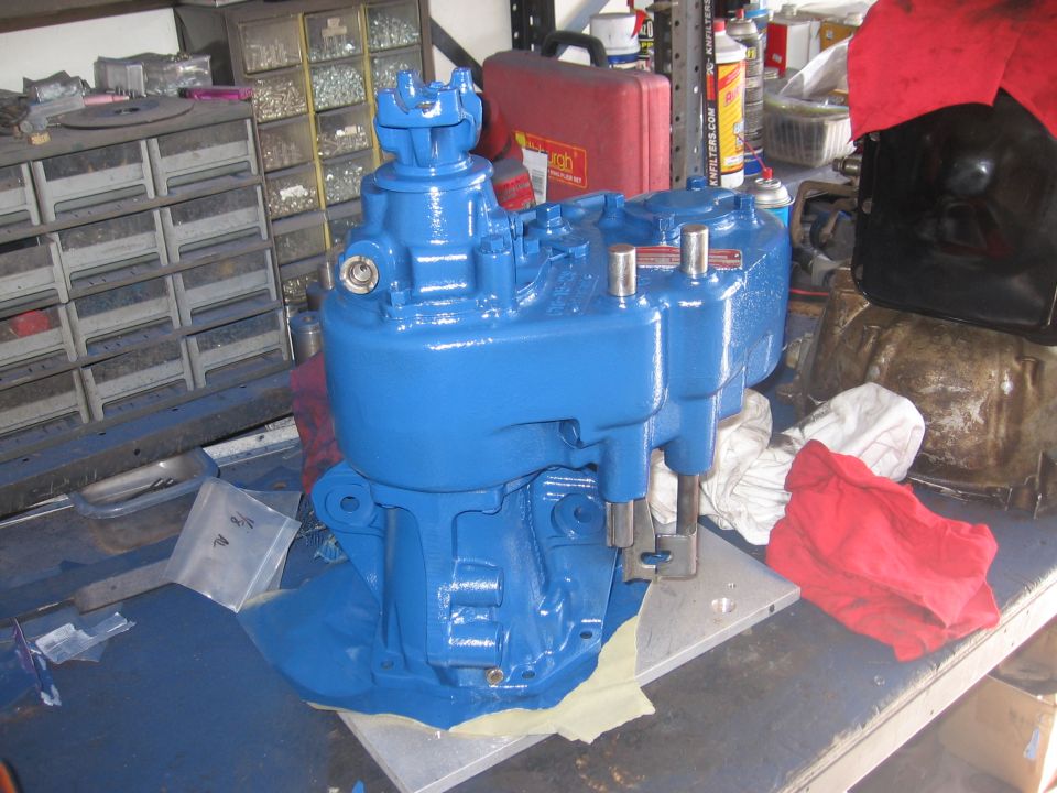 blue painted transmission sitting on a workbench with tools and rags around it
