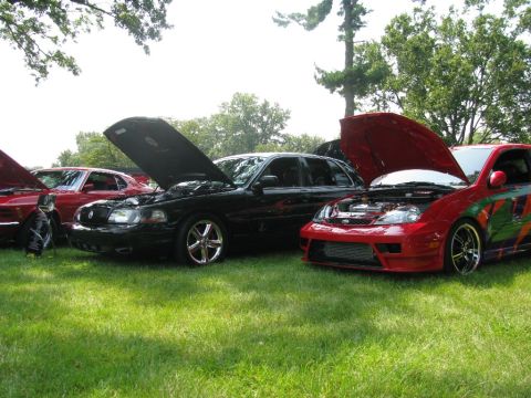 2003 Mercury Marauder - Several cars are displayed with their hoods open at an outdoor car show.