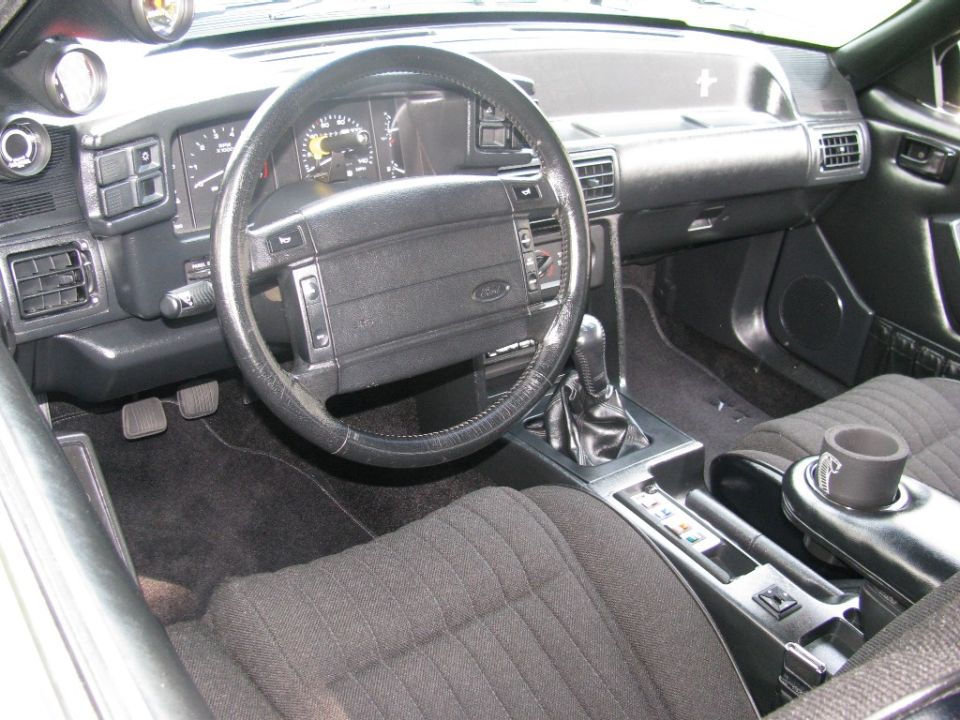 Car interior with manual shifter, aftermarket gauges, and Ford steering wheel