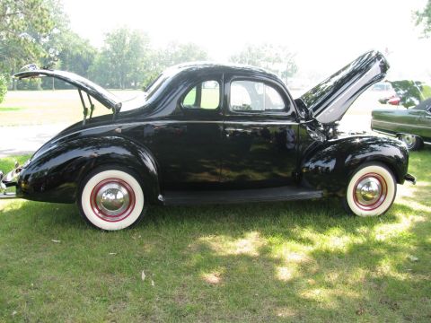2003 Mercury Marauder - A black 1939 Ford coupe is displayed with its hood and trunk open, parked on grass.